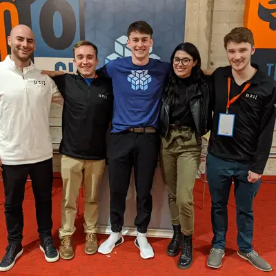Five people standing together in front of a painted mural wall.