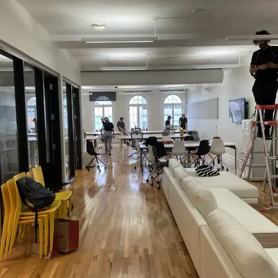 An office under construction, someone on a step ladder near the ceiling.