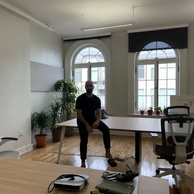 A person leaning against a desk in a mostly empty new office.