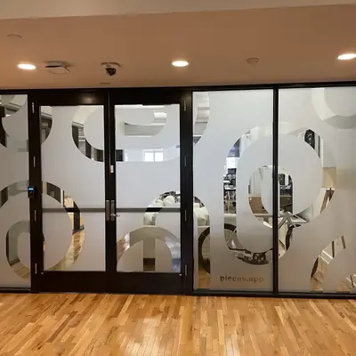 Glass double doors etched with the company logo, leading into an office.