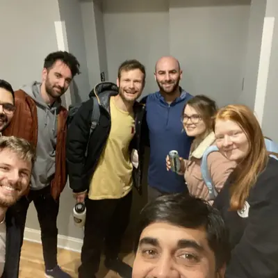 A group selfie of eight people crowded into a hallway.