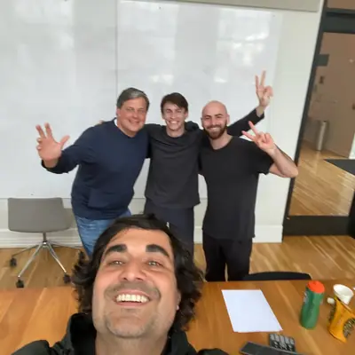 A selfie of four people in a meeting room in front of a wiped whiteboard.
