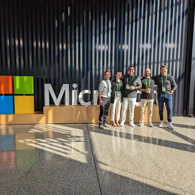 A group standing beside a large Microsoft logo sign at a conference venue.