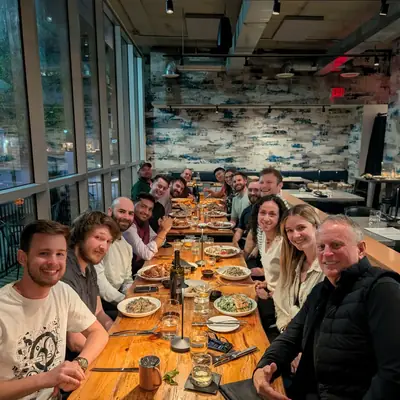 A long dinner table with around twenty people seated along both sides.